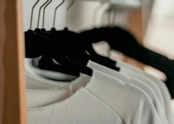 pexels-photo-2112648-2112648 Close-up of white t-shirts hanging neatly on black hangers in a minimalist indoor closet setting.